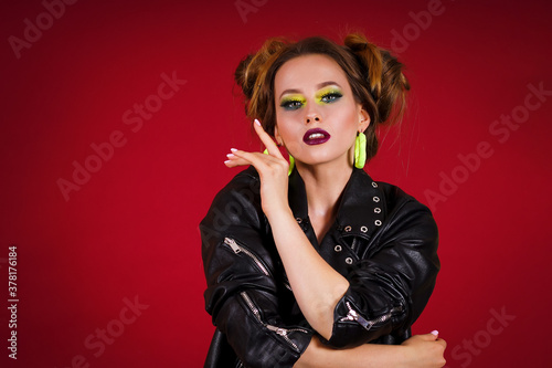 Beautiful girl with bright makeup in a black jacket on a red background