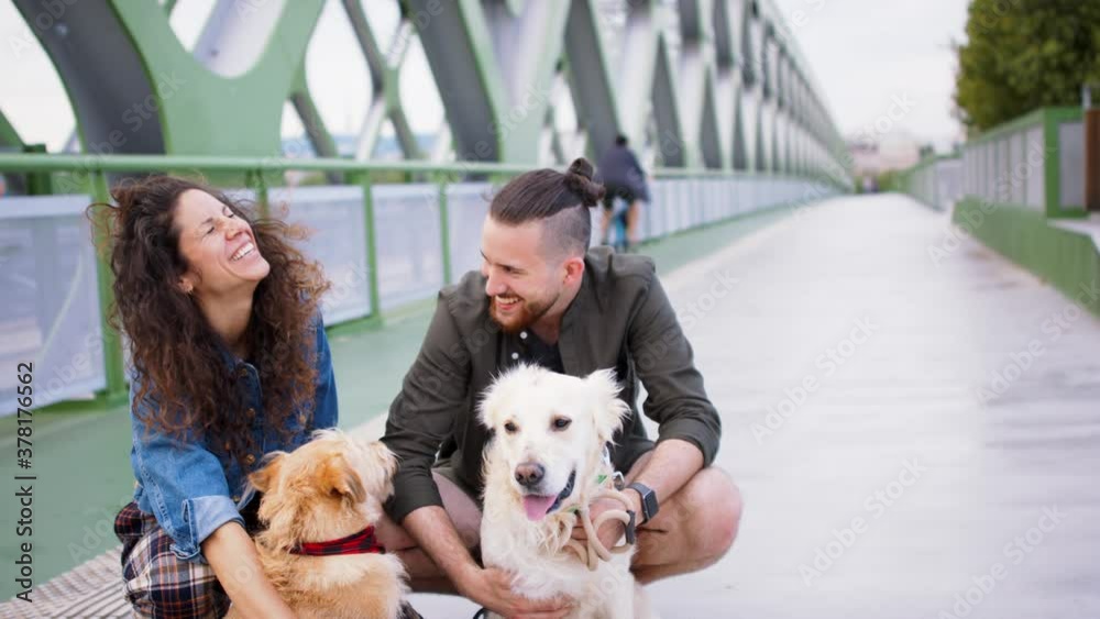 Cheerful man and woman with three pet dogs outdoors in city, laughing. Cheerful man and woman with three pet dogs outdoors in city, laughing.