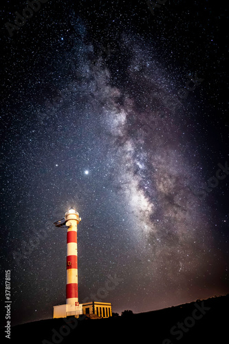 lighthouse in the sea with milky way