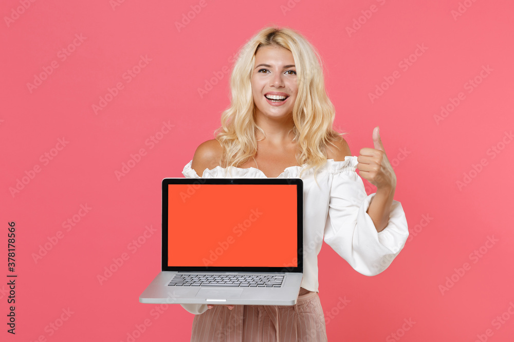 Cheerful young blonde woman 20s in white casual clothes hold laptop pc computer with blank empty screen mock up copy space showing thumb up isolated on bright pink colour background studio portrait.