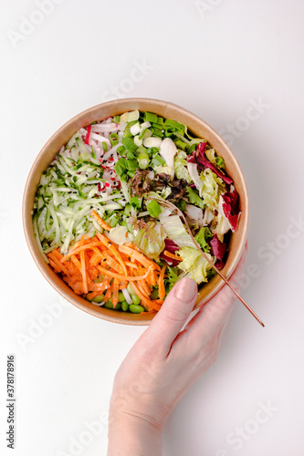 Wallpaper Mural Healthy flatlay salad in kraft paper package on white table with female hand. Vegetables and herbs cut into strips. Fitness food. Lunch. Nutrition concept Torontodigital.ca