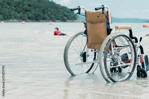 A wheelchair of disable child, Special kid is play sand and crawls happily on the beach,Blue sea background,Natural therapy,Life in the education age of disabled children,Happy disability boy concept.