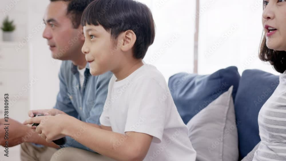 Close up happy asian family play video game at home feeling excited fun holding console in hand in quarantine activity, entertainment at home concept. Competition and funny in leisure time or hobby. Close up happy asian family play video game at home feeling excited fun holding console in hand in quarantine activity, entertainment at home concept. Competition and funny in leisure time or hobby.