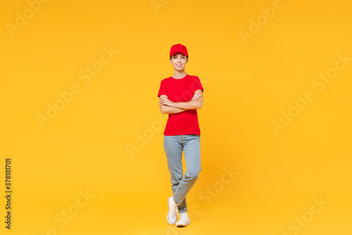 Full length body delivery employee woman in red cap blank t-shirt uniform work courier in service during quarantine coronavirus covid-19 virus standing isolated on yellow background studio portrait.