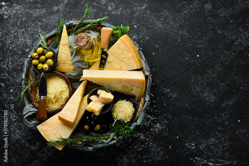 Set of hard cheeses with cheese knives on black stone background. Parmesan. Top view. Free space for your text. photo