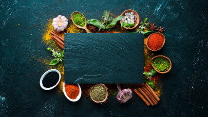 Colorful herbs and spices for cooking. Indian spices. On a black stone background. Top view.