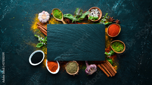 Fototapeta Naklejka Na Ścianę i Meble -  Colorful herbs and spices for cooking. Indian spices. On a black stone background. Top view.