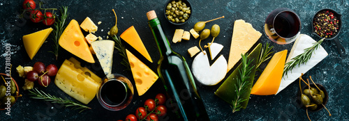 Wine, cheese and snacks on a black stone background. Assorted cheese. Top view. Free space for your text. photo