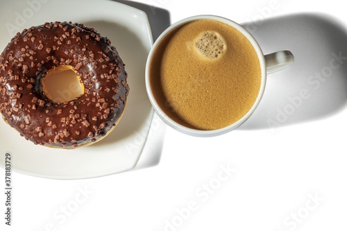 Close up view of cup of coffee and chocolate donut. Food and drink concept.