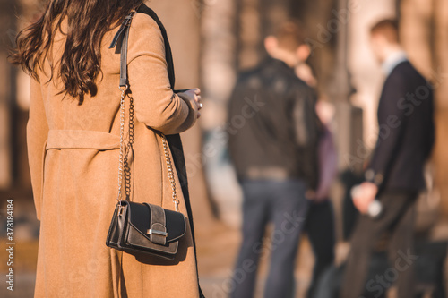 rear view of woman in brown topcoat walking by street