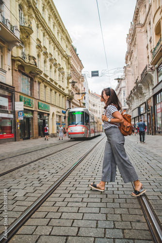 woman walking by brno old town street modern public tram on background
