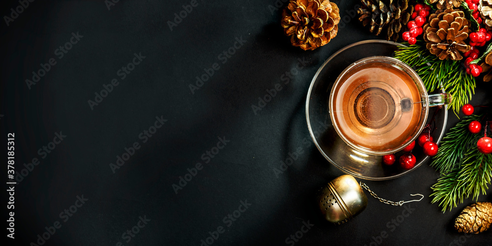 Christmas tea and christmas decoration on black background from above. Cozy winter hot beverage and december pine cones decor on dark table. Top view.