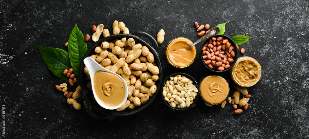 Peanut butter and nuts on a black stone background. Healthy food. Top view. Peanut butter and nuts on a black stone background. Healthy food. Top view.