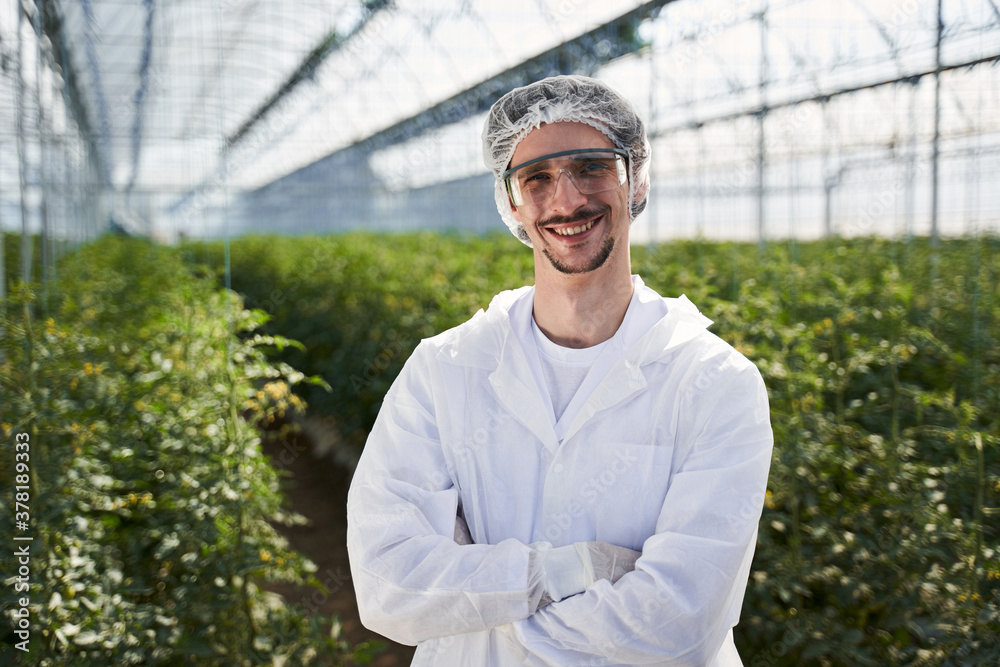 Smiling young man working with plants in greenhouse