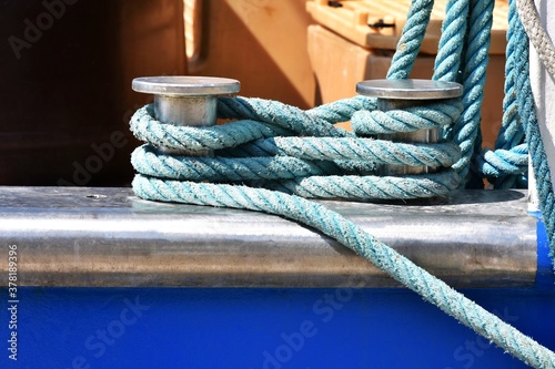 Chrome double bollard with blue mooring rope on the navy ship, close up. photo