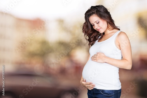 A pregnant young woman in white t-shirt on bright background