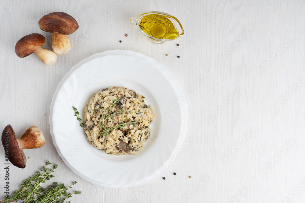 Φωτογραφία Top view of creamy risotto or Italian arborio rice dish cooked with broth containing mushrooms, thyme, white wine, olive oil and parmesan cheese on white wooden background