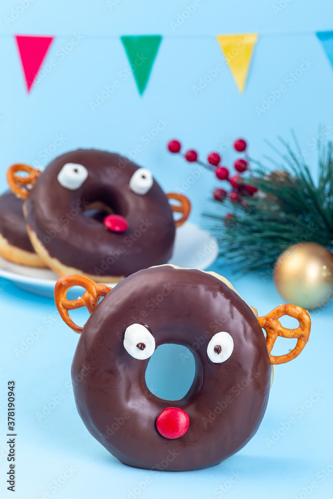 Christmas reindeer made from chocolate doughnut, pretzel cookie, marshmallow and candy, Christmas menu for kids, vertical