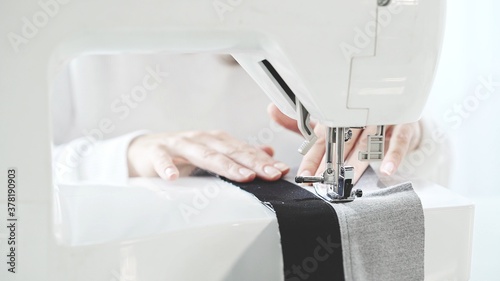 Fotografering Female hands sew on a white sewing machine close-up