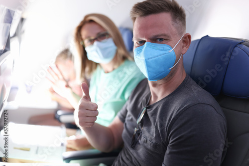 Husband and wife are flying on plane wearing medical masks. Sanitary standards of flight during epidemic of coronavirus infection concept.