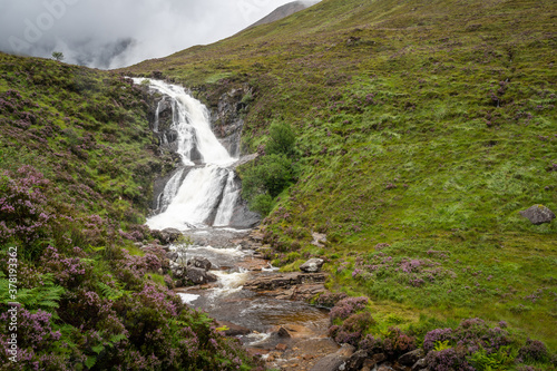 View of Blackhill waterfall on Isle of Skye, Scotland. Blooming purple heather growing along a stream