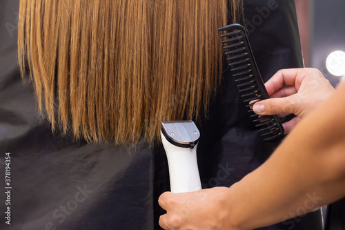 Hairdresser with a hair machine. cutting off split ends of hair with a clipper. close up.