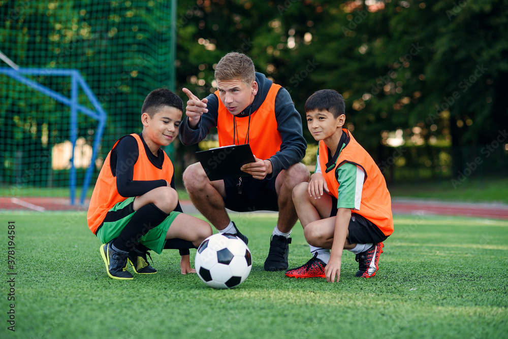 Football coach instruct teen football players. Young professional coach