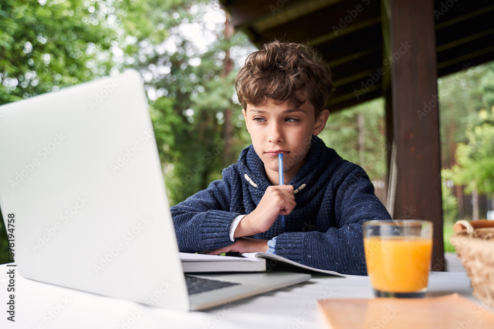 Adorable boy using notebook while studying outdoors Adorable boy using notebook while studying outdoors
