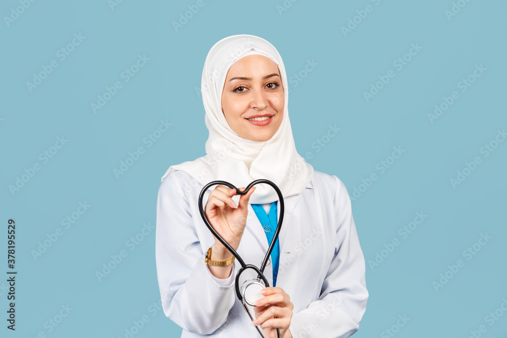 friendly, Muslim doctor or nurse woman in hijab with a heart shaped stethoscope. on a blue background.