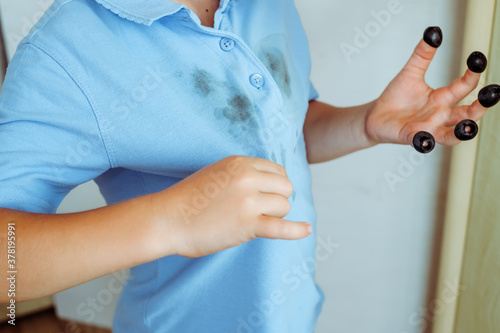 A boys is showing a stain on his clothes  black olives on each finger of his hand The concept of cleaning stains on clothes. Isolated on a white background