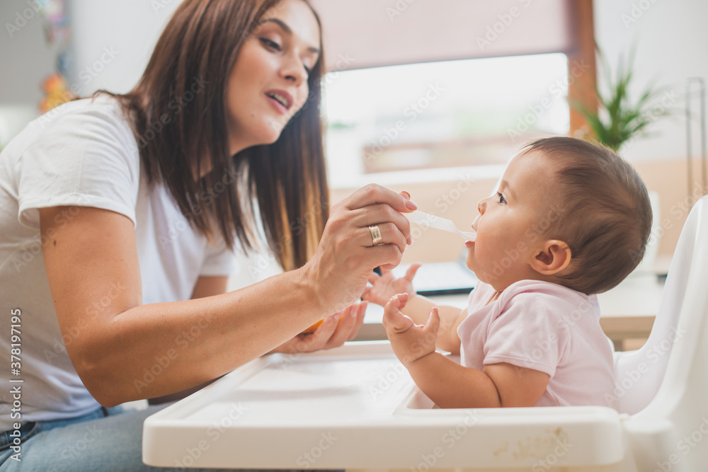 Mother feed her little daughter with a spoon Mother feed her little daughter with a spoon