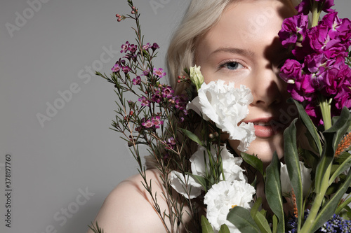 Beautiful young woman holding colorful blooming plants