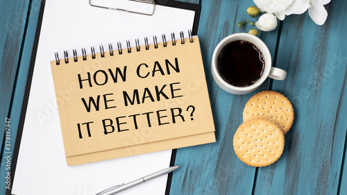 Text sign showing How Can We Make It Better question. Conceptual photo asking how increase quality of product Man holding marker notebook clothespin reminder wooden table cup coffee. photo