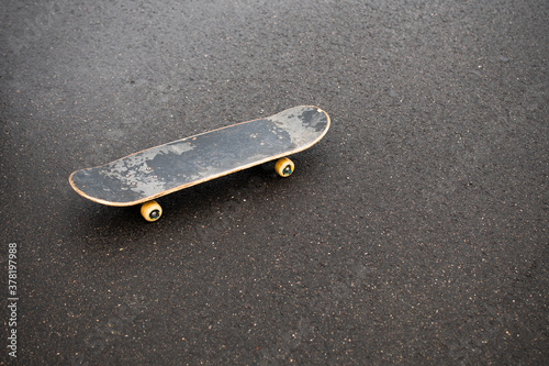 the skateboard stands on the gray asphalt. old skate. skateboard for tricks and riding. place for the test photo