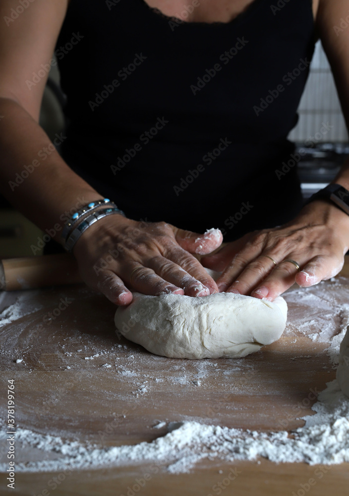 Preparare la pasta fatta in casa. Mani di donna impastare pasta fresca per fare il pane o la pizza su un tavolo infarinato.