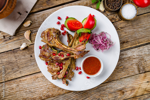 kebab from a rack of lamb with tomato sause on white plate on old wooden table top view photo