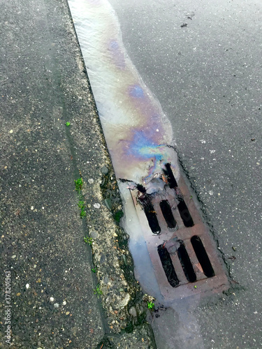 Leaking car oil draining into street sewer during rain storm