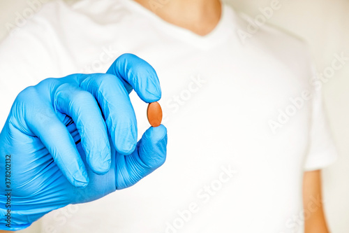 Hands doctor's in medical gloves hold a red pill. Blue disposable gloves isolated on a white background. Pharmaceutical concept. medicine, research concept
