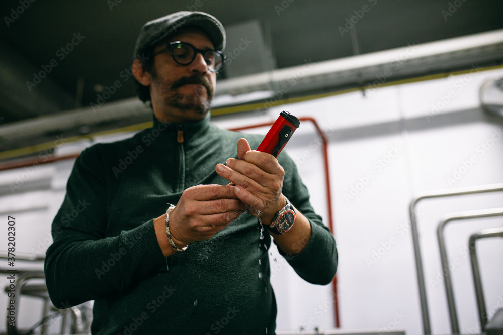 Male brewer using manual hydrometer