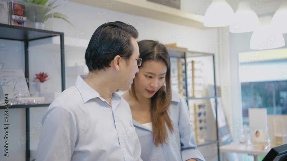Optical shop concept. Asian couple testing glasses in a shop. 4k Resolution. Optical shop concept. Asian couple testing glasses in a shop. 4k Resolution.
