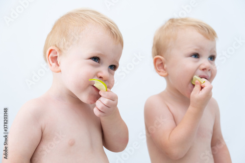 cute twin boys toddler baby tasting lime slices.