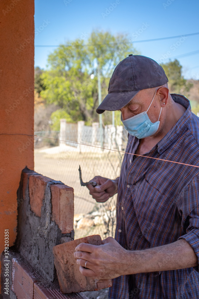 Man with chinstrap working on brick construction Man with chinstrap working on brick construction