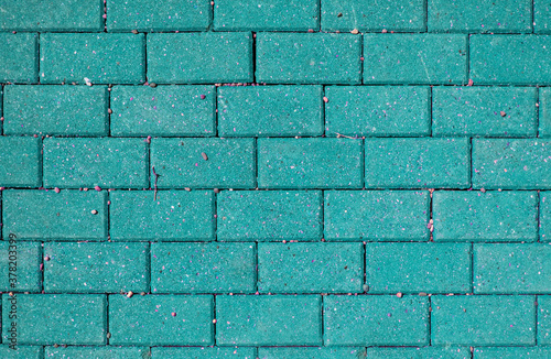 Bright green brick wall with pink splashes and pebbles, abstract brick background