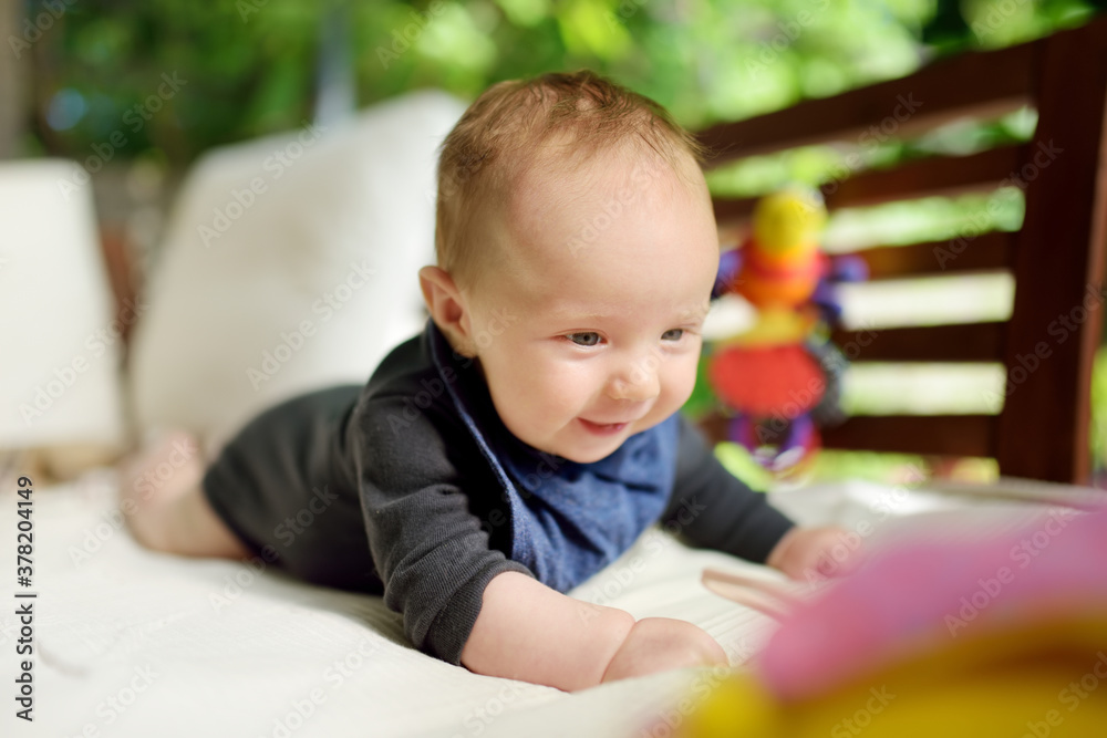 Cute three months old baby boy playing with his toys outdoor. Baby during tummy time. Cute little child learning to crawl. Cute three months old baby boy playing with his toys outdoor. Baby during tummy time. Cute little child learning to crawl.