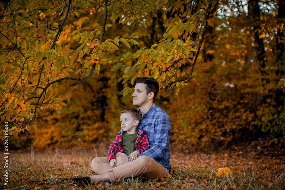 Happy family having fun outdoor in autumn park. Father and son against yellow blurred leaves background. Happy family concept, Father's Day
