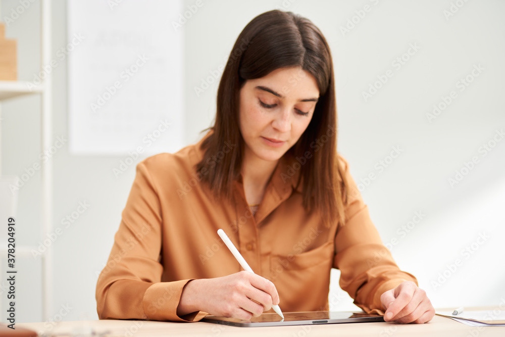 Serious female freelancer drawing on modern tablet Serious female freelancer drawing on modern tablet