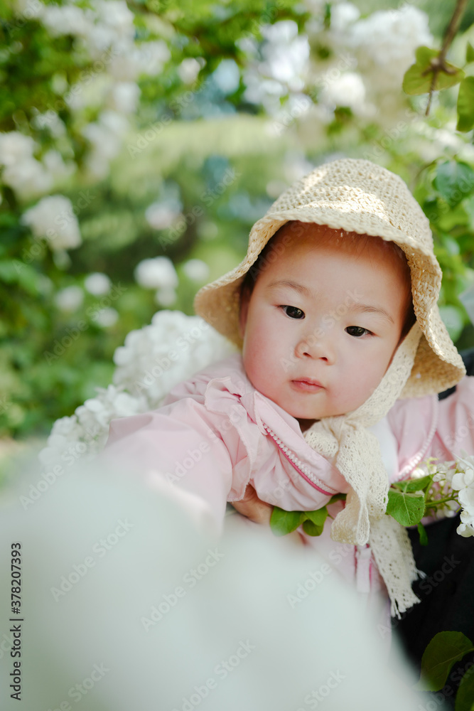 Little girl wearing straw hat on wooden hydrangea background in spring sunshine Little girl wearing straw hat on wooden hydrangea background in spring sunshine