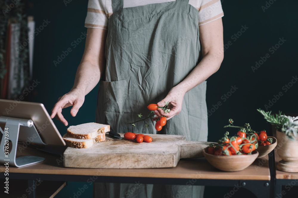 Anonymous Woman Choosing Tomatoes While Following Recipe On Tablet Anonymous Woman Choosing Tomatoes While Following Recipe On Tablet