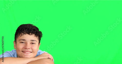 Handsome young boy against green backgroud looking at the camera and smiling