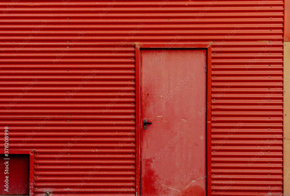Fachada metálica de almacén industrial con puerta roja Fachada metálica de almacén industrial con puerta roja